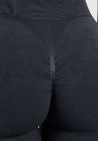 Gros plan sur un legging noir sans couture à taille haute avec des motifs tricotés texturés autour de la taille et des hanches.