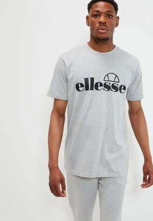 Camiseta gris de manga corta con un logo negro de "ellesse". Fabricada con una tela suave, con un corte holgado y un clásico cuello redondo.