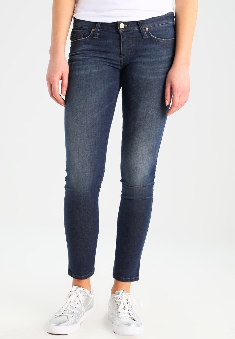 Smal passform, mörkblå denimjeans med en blekt tvätt, med fem fickor och kopparfärgad hårdvara, i kombination med silvriga sneakers.