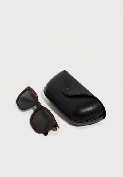 Ορθογώνια γυαλιά ηλίου με μοτίβο χελωνόφλουδας και σκουρόχρωμους φακούς δίπλα σε μαύρη δερμάτινη θήκη προστασίας με κούμπωμα πάνας.