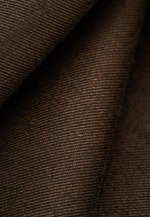 Brauner Cordstoff, gefaltet, zeigt weiche Textur und feine vertikale Rillen in Nahaufnahme.