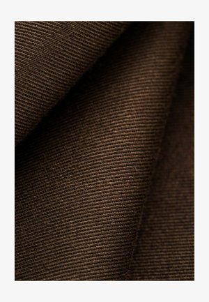 Brauner Cordstoff, gefaltet, zeigt weiche Textur und feine vertikale Rillen in Nahaufnahme.