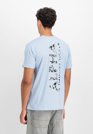 Hellblaues Baumwoll-T-Shirt mit einem großen, reflektierenden "ALPHA"-Grafik in Tarnmuster auf der Rückseite. Kurzärmlig, mit Rundhalsausschnitt.