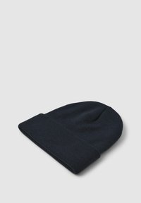 Cappello in maglia color blu navy scuro con risvolto, posato su uno sfondo grigio chiaro.