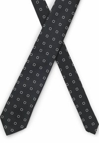 Czarny krawat z teksturowanej tkaniny z małymi, powtarzającymi się białymi kwadratowymi wzorami. Krawat ma lekko zaostrzony koniec.
