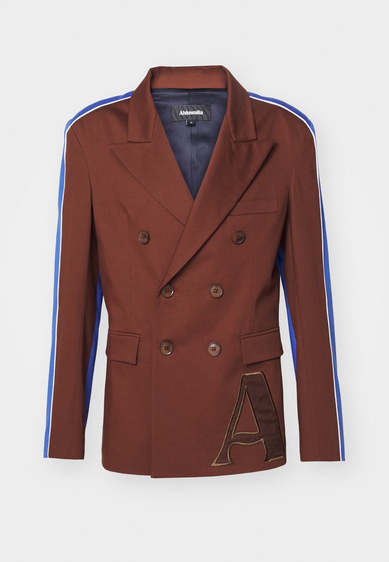 Blazer doppio petto marrone con strisce laterali blu e bianche, caratterizzato da grandi bottoni marroni e un accento ricamato a forma di "A" sul davanti.
