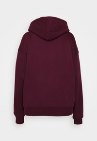 Sudadera con capucha color granate de corte holgado, con una textura suave, puños y dobladillo acanalados, sin logotipos ni estampados visibles.