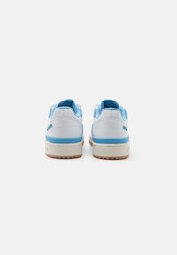 Ett par vita och ljusblå sneakers som visas bakifrån mot en enkel vit bakgrund.