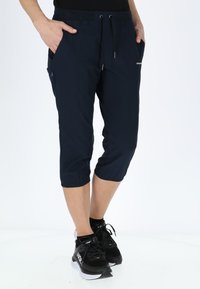 Pantaloni capri navy realizzati in materiale leggero, dotati di vita con cordoncino, due tasche laterali e polsini elasticizzati con un branding discreto.