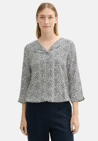 Blaue und weiße gemusterte Bluse mit V-Ausschnitt, Dreiviertelärmeln und lässiger Passform, gefertigt aus leichtem Stoff.