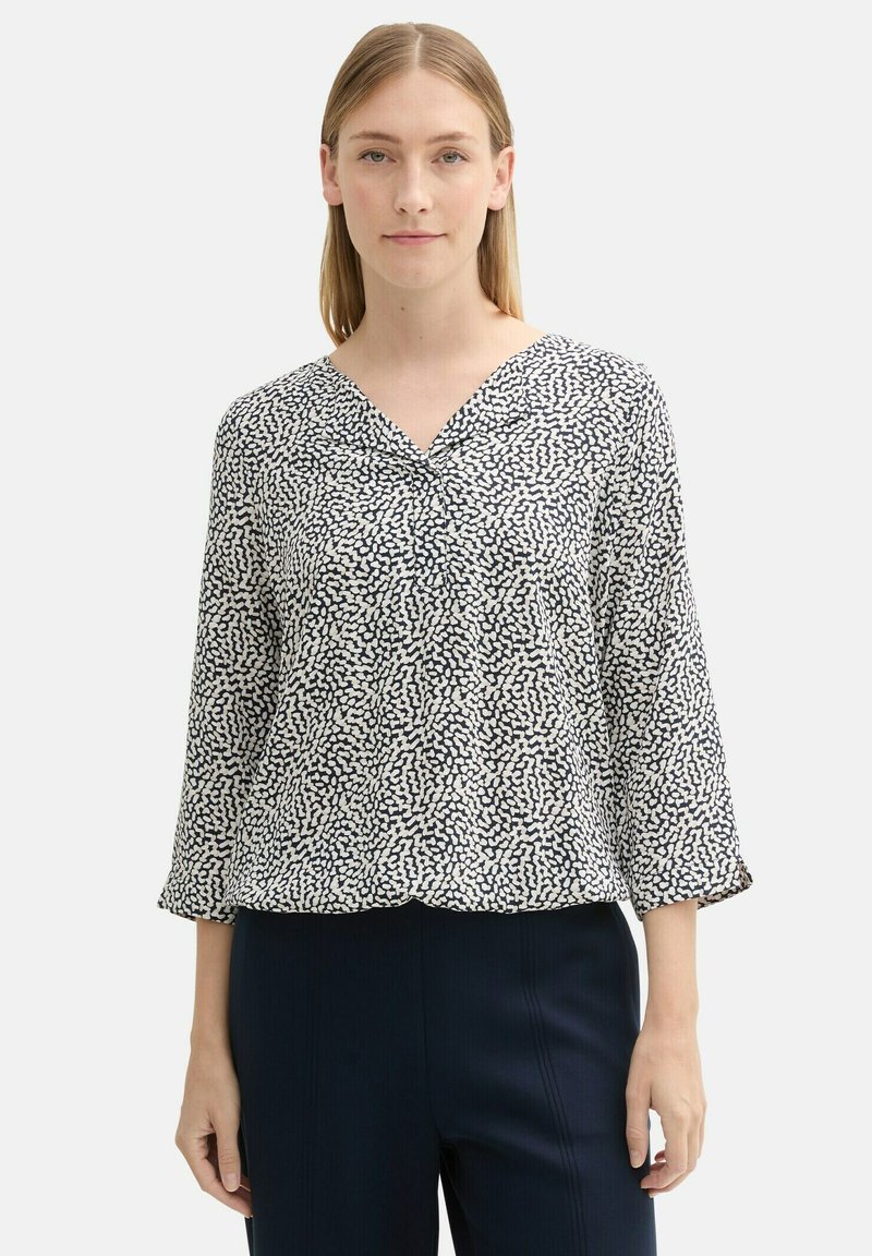 Blaue und weiße gemusterte Bluse mit V-Ausschnitt, Dreiviertelärmeln und lässiger Passform, gefertigt aus leichtem Stoff.