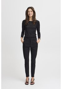 Black lace top with long sleeves, paired with tailored black pants. Model wears strappy black sandals. Simple and fitted design.