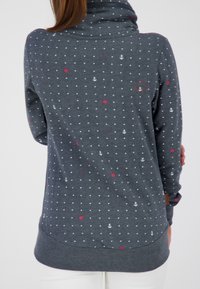 Pullover grigio chiaro con colletto alto, caratterizzato da pois bianchi, motivi floreali rossi e piccoli motivi a ancora. Tessuto strutturato con orlo curvo.