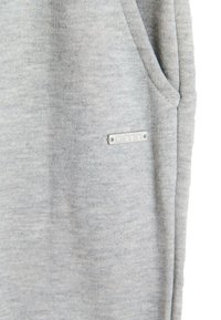 Grå bomulds sweatshirt med en struktureret overflade, der har en sidelomme og et lille sølvfarvet mærke fastgjort.
