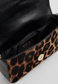 Kabelka DKNY se leopardím vzorem, vyrobená z texturované hnědé a černé látky, s zlatým zapínáním na patent a černým koženým interiérem s logem.