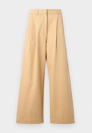 Beige vidde ben bukser laget av myk bomull, med flat front, folder og synlige sidelommer.