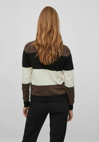 Stickad tröja med horisontella ränder i brunt, svart och krämfärgat. Har en rund halsringning och ribbade muddar och nederkant.