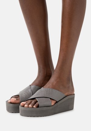 Gray wedge sandals with cross straps. Made from textured material. Platform sole with a slight gradient and a textured underside.