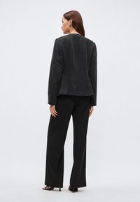 Čierne, textúrované sako s pevnou konštrukciou, v kombinácii so širokými čiernymi nohavicami. Sakó má jednoduchý, čistý strih.