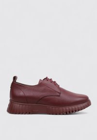 Zapatos de cuero burdeos con parte superior texturizada, puntera redondeada y suela gruesa con estrías. Cuenta con cuatro ojales y una lengüeta en el talón.