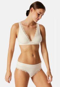 Bralette beige clair et culotte bikini assortie avec bordures en dentelle, tissu doux et décolleté en V.