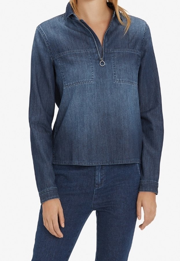 Femme portant une chemise en denim bleu foncé à manches longues avec une fermeture éclair à l'avant et un jean en denim bleu foncé assorti.