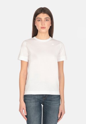 T-shirt bianca aderente con maniche corte, collo rotondo, realizzata in morbido cotone. Presenta un piccolo logo sul petto sinistro e orli arrotolati.
