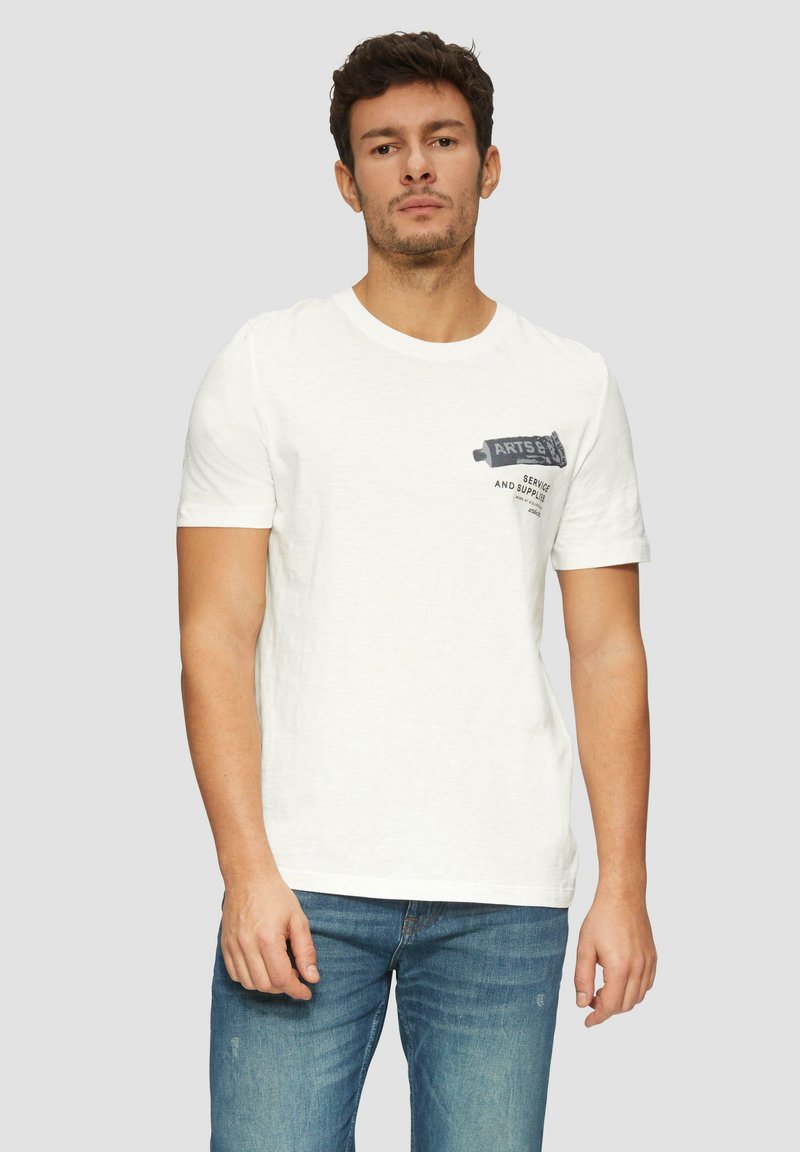 Witte katoenen t-shirt met korte mouwen, voorzien van een grafische print op de linkerborst. Gecombineerd met blauwe spijkerbroeken.