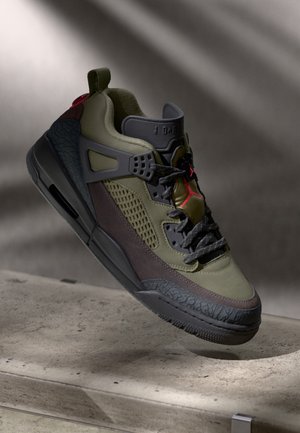 Baskets montantes en vert olive, noir et marron avec une semelle texturée et un logo Jumpman rouge, présentées sur un fond neutre.