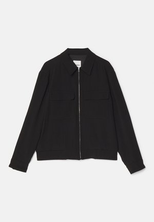 Zwarte ritsjacket gemaakt van gestructureerde stof. Kenmerken zijn een kraag, twee voorkruiken en ribgebreide manchetten met een aansluitende zoom.