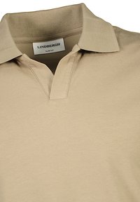 Polo shirt slim fit beige realizzato in tessuto morbido. Presenta un colletto classico e una chiusura con tre bottoni.