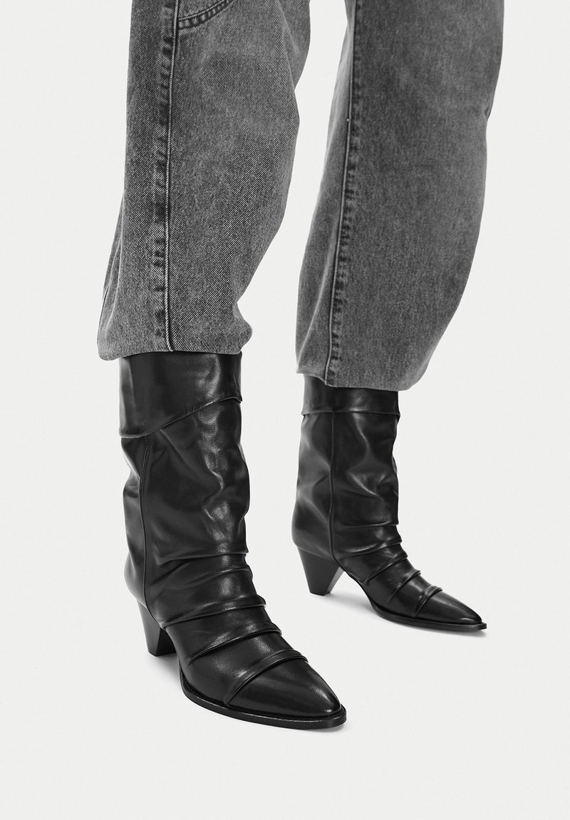 Czarne skórzane botki na kostkę z luźnym fasonem, szpiczastym noskiem i skromnym, układanym obcasem, z zmarszczoną fakturą i poziomymi szwami.