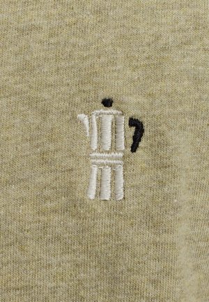 Un tissu en coton de teinte olive claire présente un motif de cafetière moka brodé en fil blanc et noir, mettant en avant la texture et le savoir-faire.