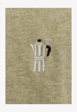 Un tissu en coton de teinte olive claire présente un motif de cafetière moka brodé en fil blanc et noir, mettant en avant la texture et le savoir-faire.