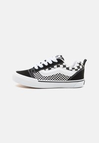Sneakers in bianco e nero con un design a scacchi, suole in gomma, lacci bianchi e una texture di tessuto liscia con dettagli di cucitura laterale.