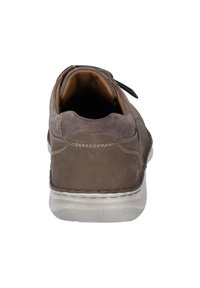 Chaussure en suède marron avec une semelle en caoutchouc, forme arrondie, col matelassé et couture décorative. L'intérieur est doublé en matériau beige.