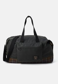 Dark green Barbour duffel bag with black handles, front pocket, adjustable shoulder strap, and tartan-patterned bottom edge.