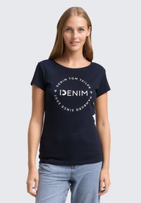 Jūrų kariuomenės t-shirt iš medvilnės su apvaliu kaklu ir trumpomis rankovėmis, su centriniu grafiniu dizainu baltos ir mėtų žalios spalvos. Kasdienis pritaikymas.