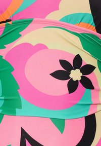 Maillot de bain multicolore avec des motifs floraux roses, verts et noirs, doté d'une texture lisse, de coutures contrastantes et d'un design ajusté.