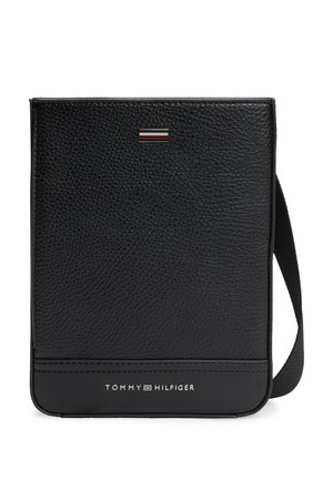 Schwarze Crossbody-Tasche aus genarbtem Leder mit verstellbarem Riemen, Tommy Hilfiger-Logo und Metallflaggenemblem auf der Vorderseite.
