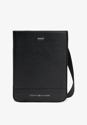 Schwarze Crossbody-Tasche aus genarbtem Leder mit verstellbarem Riemen, Tommy Hilfiger-Logo und Metallflaggenemblem auf der Vorderseite.