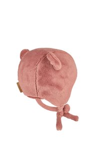 Pink fleece bear hat with rounded shape, small ears, and chin ties. Soft texture with a smooth finish and a tag on the side.