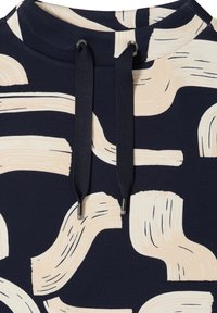 Sweat à capuche bleu marine avec un motif abstrait de coups de pinceau crème, doté d'un cordon de serrage aux embouts argentés et d'une finition en tissu texturé.