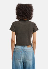 Σκούρο γκρι κοντομάνικο τοπ με rib ύφανση, στρογγυλή λαιμόκοψη, σε συνδυασμό με ανοιχτό μπλε τζιν ψηλόμεσο παντελόνι με επένδυση σε ταμπά χρώμα.