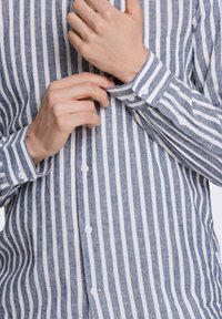 Blauw-witte gestreepte shirt met lange mouwen, knoopmanchetten en een zak. Gemaakt van een gestructureerde stof met een ontspannen pasvorm.