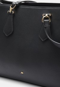 Borsa a spalla in pelle nera con superficie texturizzata, dotata di hardware in tonalità oro e due attacchi per le cinghie. Piccolo logo visibile sul fronte.
