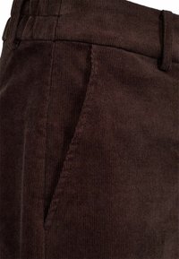 Brūni korduroja bikses ar vertikālu ribojumu, pielāgotu jostu ar cilpiņām un sānu kabatu. Materiāls ir mīksts un patīkams.