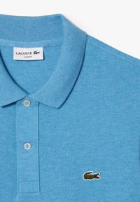 Svetlo modra slim fit polo majica z rebrastim ovratnikom, dvema gumboma in zeleno vezenim krokodilom na levem prsnem delu.