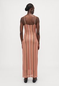 Striped maxi dress with thin straps, crafted from a lightweight, textured fabric in warm hues of peach, pink, and cream.