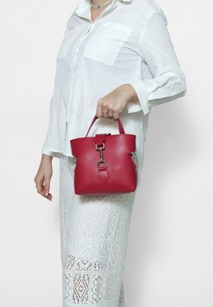 Rote Lederhandtasche in runder Form, mit einem oberen Griff, metallischen Beschlägen und einem dekorativen herzförmigen Detail. Glatte Textur.